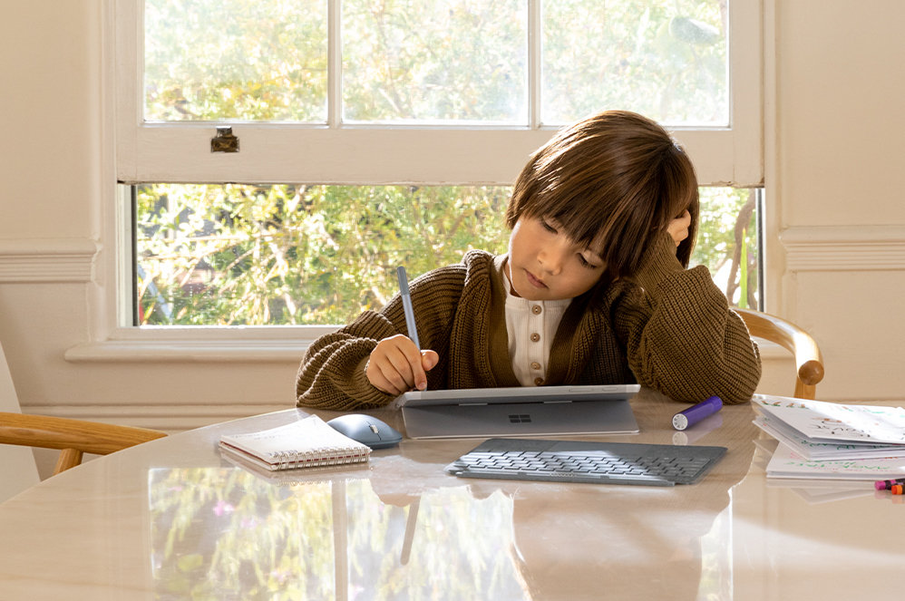 Een man aan tafel houdt een Surface Go 2-scherm vast