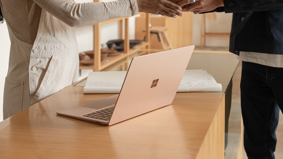 A ceramics artist uses Surface Laptop 3 while selling products to a customer.