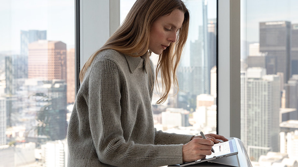  uma mulher a trabalhar numa apresentação com o Surface Pro 7 para Empresas e a Caneta para Surface