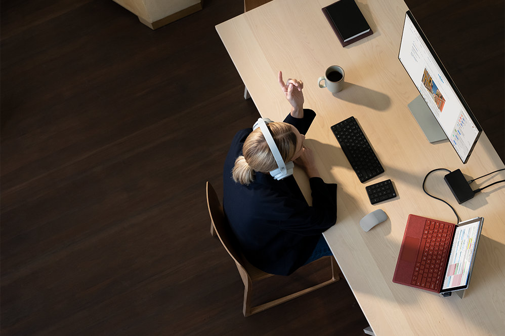 Top-down view of a person wearing a headset while attending an online meeting on a Surface Pro 7+.
