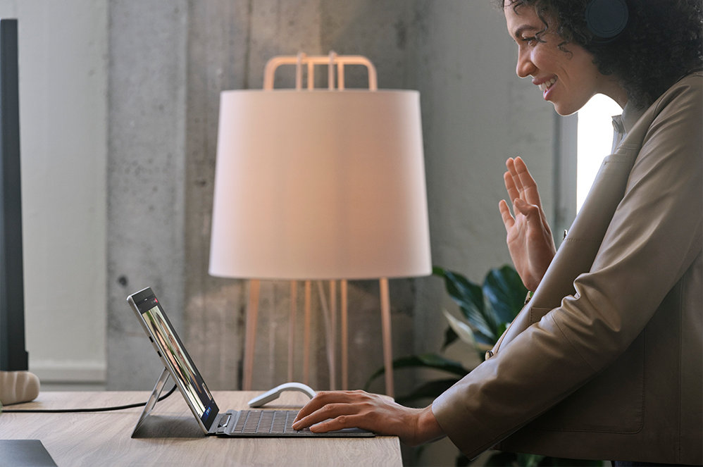 A person standing at a desk working with Surface Pro X for Business.