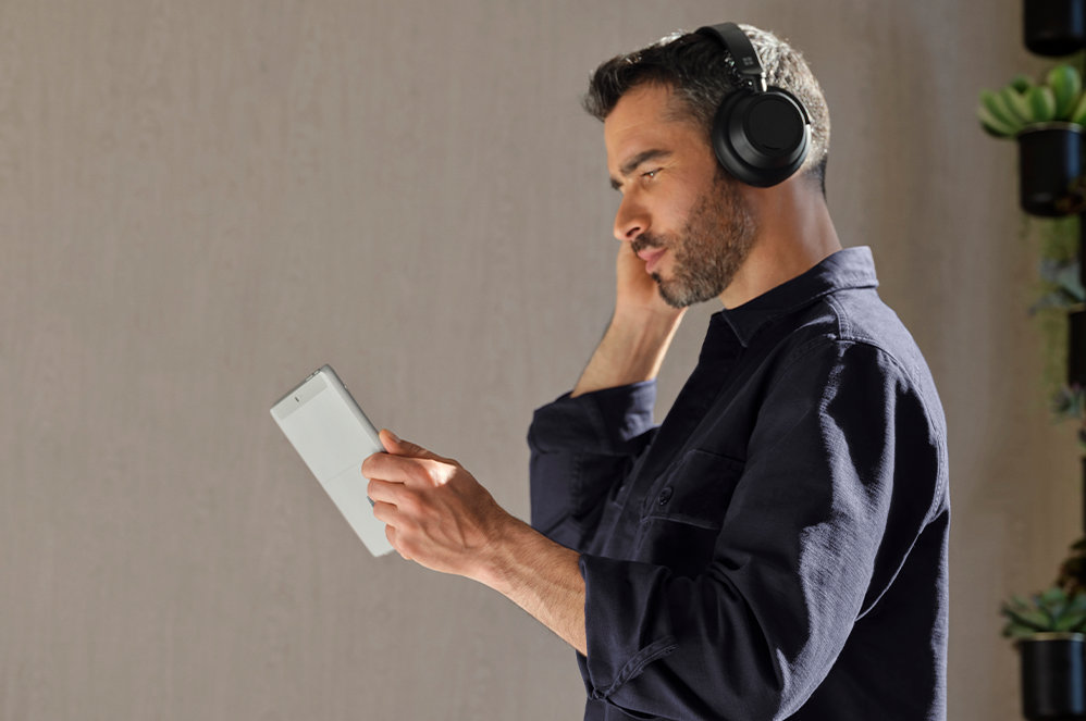 A person holding Surface Go 3 for Business and wearing Surface Headphones