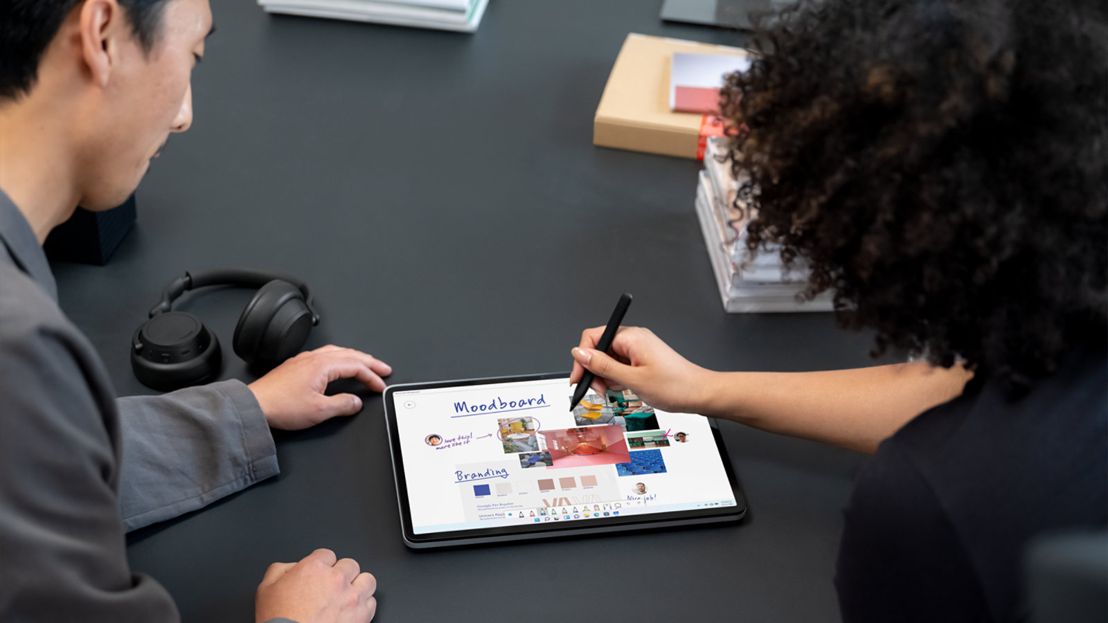 Dos personas trabajan con un dispositivo Surface Laptop Studio para empresas, una de ellas sostiene Surface Slim Pen 2 para empresas.