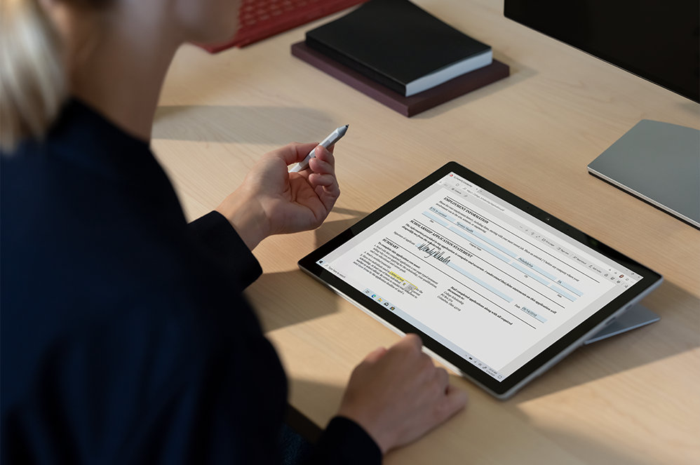 A person signing a contract on a Surface Pro 7 plus for Business with a Slim Pen 2.