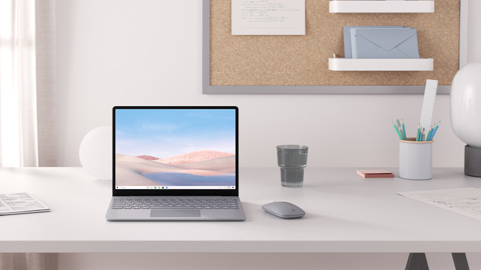 A platinum Surface Laptop Go and Microsoft Modern Mobile Mouse rest upon a desk.