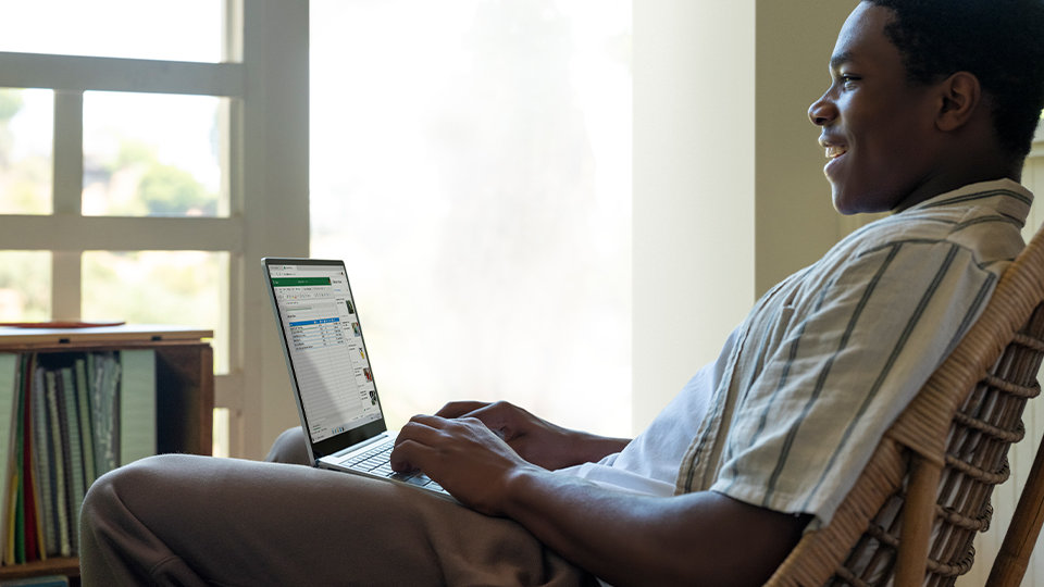 A man sits at his desk looking at his Surface Laptop Go for Business.