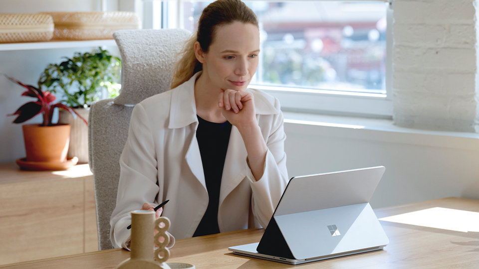 Una persona seduta a una scrivania osserva un dispositivo Surface Laptop Studio per le aziende.