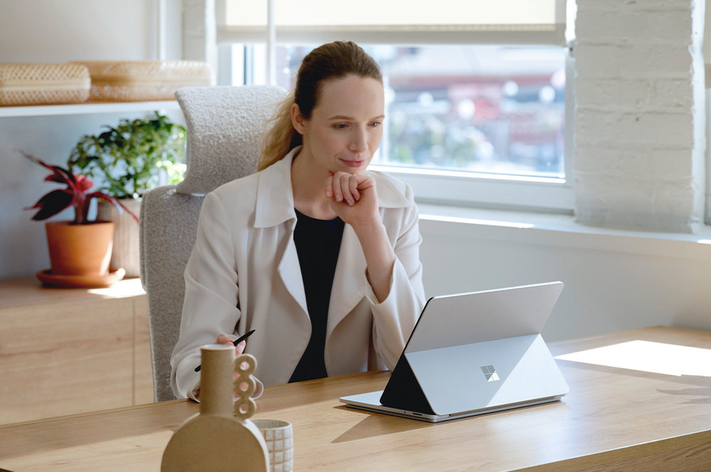 Une personne assise à un bureau regardant le Surface Laptop Studio pour les entreprises.