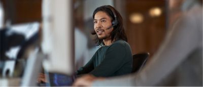 A person wearing a headset and looking at a computer