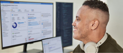 Eine Person, die sich den Bildschirm am Desktop ansieht und lächelt.