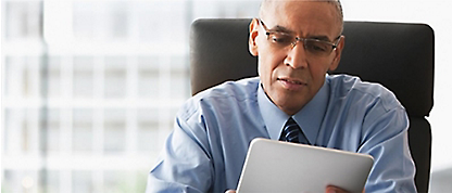 Un hombre sentado en una oficina mirando una tableta.