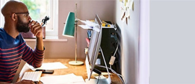 A man sitting at a desk looking at a computer screen.