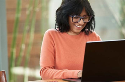 A person in glasses smiling at a computer