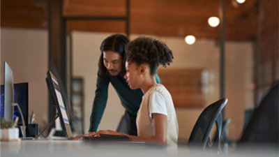 Dwoje współpracowników rozmawiających o pracy przy komputerze w nowoczesnym środowisku biurowym