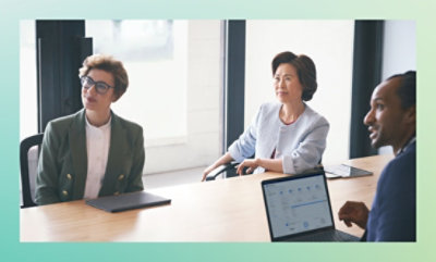 Three people are sitting around a table in a meeting room.