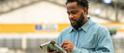 A man using a tablet in a warehouse.