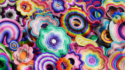 A brightly colored custom background for Teams with a floral shapes inunique color-coded shapes representing different groups of people for Pride.