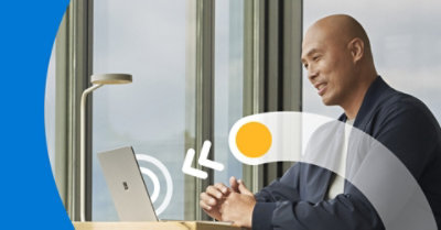 坐在桌前，兩手合攏並對著膝上型電腦微笑的人。