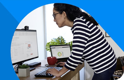 A person standing at a desk looking at a monitor displaying sign-in credentials information.