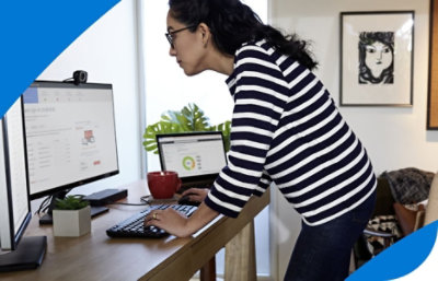 A person standing over a desk typing on a keyboard.