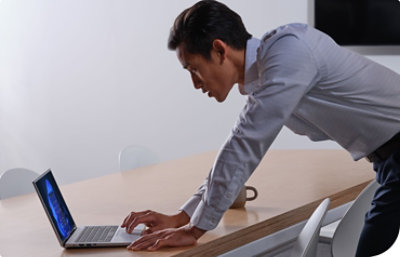 Multiple people standing around a desktop monitor having a conversation.