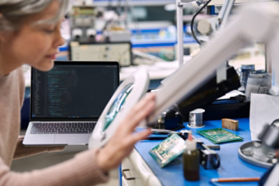 Computer science researcher inspecting CPU board through magnifier.