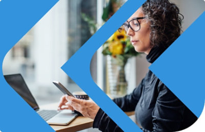 Una persona usando un teléfono celular y una portátil.