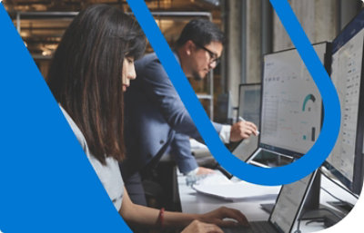 Dos personas trabajando en escritorios contiguos y mirando los datos que se muestran en las pantallas.