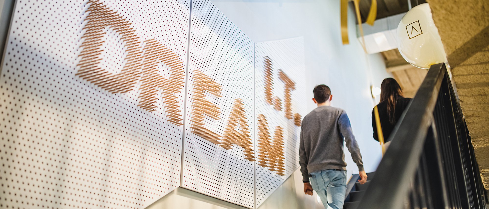 Dos personas subiendo las escaleras con una pancarta de IT dream en la pared