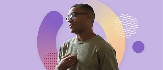 A man in glasses is standing in front of a purple background.