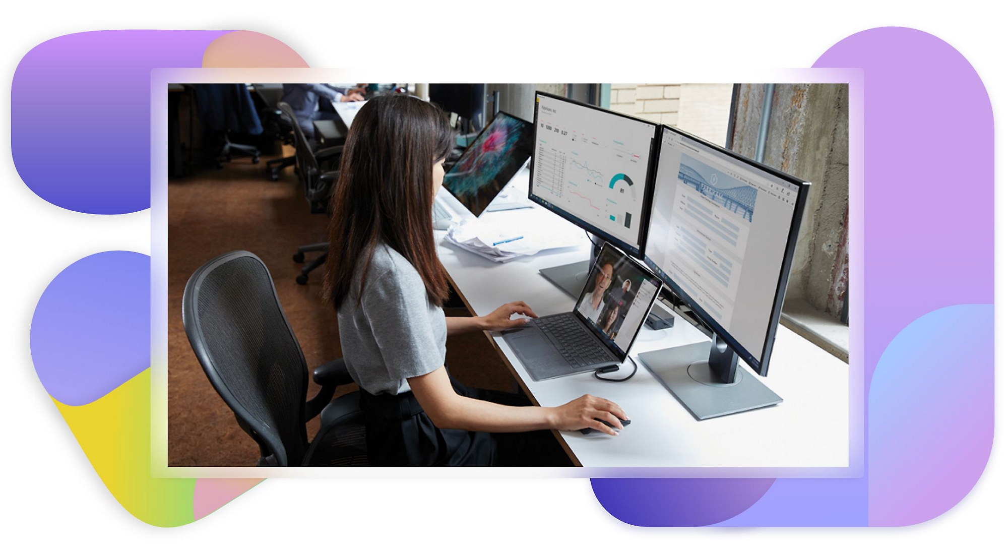 Una persona trabajando en su escritorio con un portátil y dos monitores de escritorio.