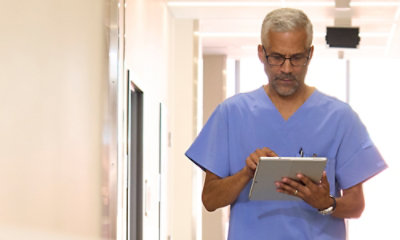 Un médecin en blouse bleue utilisant une tablette.