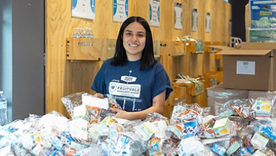 Volunteer from Northwest harvest unpacking small bags of food supplies in a large room.