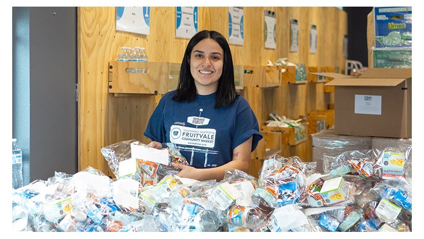 Volunteer from Northwest harvest unpacking small bags of food supplies in a large room.
