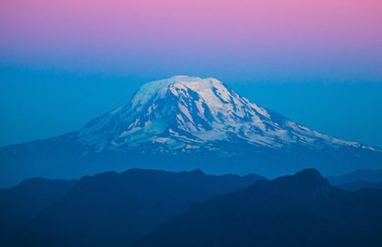 Mount Rainier in Washington State, USA, snowcapped and showing pastel bands of color at dusk.