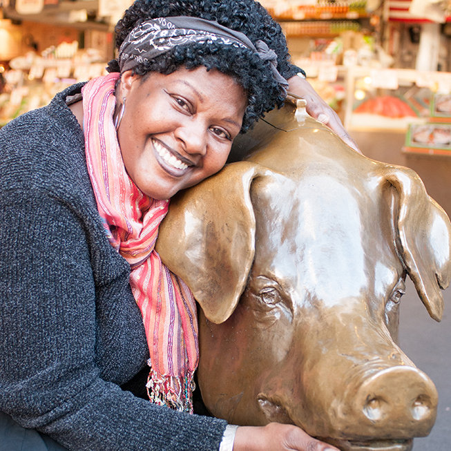 Woman next to Pike Market pig smiling at camera.