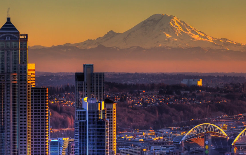 A panoramic view of the Seattle Waterfront at sunset against the backdrop of Mount Rainier.