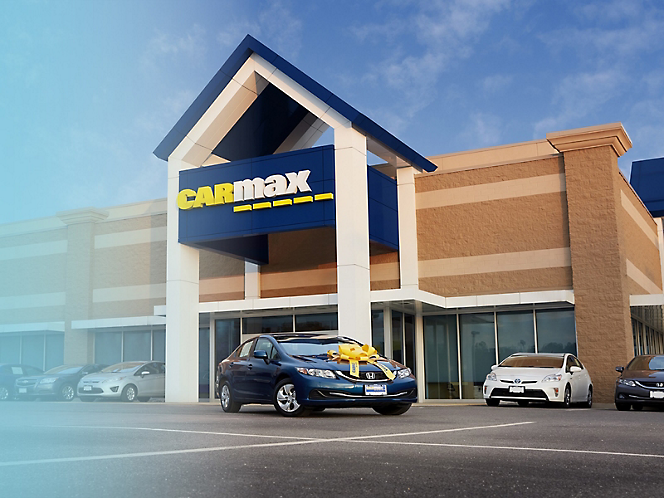 A carmax car dealership with a blue car parked in front of it