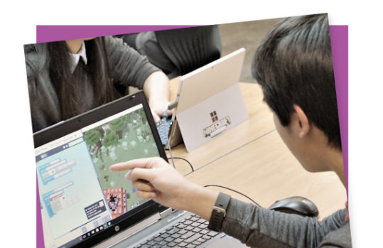 A student works on a MakeCode project on a laptop.