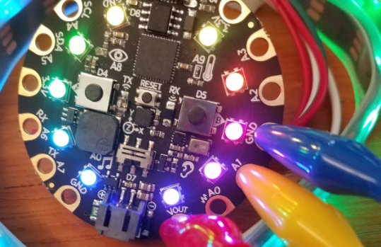 O hardware do Circuit Playground Express iluminado com diferentes cores de luzes.