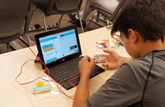 En ung student jobber med Chibi Chip-maskinvaren i et klasserom.