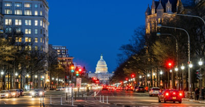 Traffic at night on a busy street in Washington, DC, with the United States Capitol building in the background.