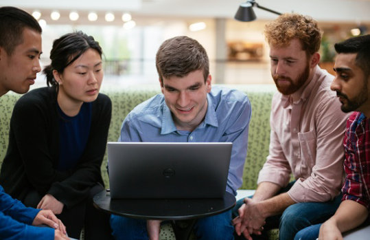 A woman and two men collaborate while looking at a computer screen