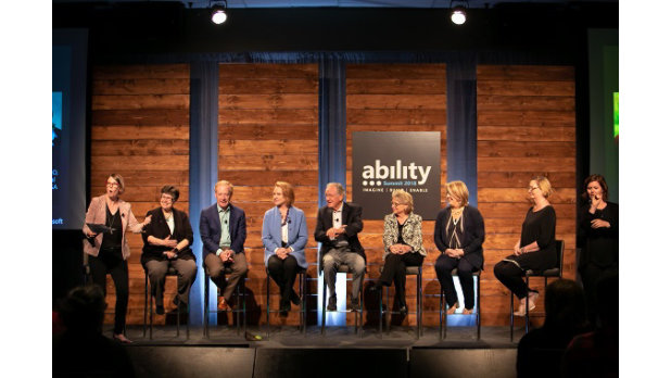 A group of people on stage during a panel and the words Ability Summit 2018 is in the background