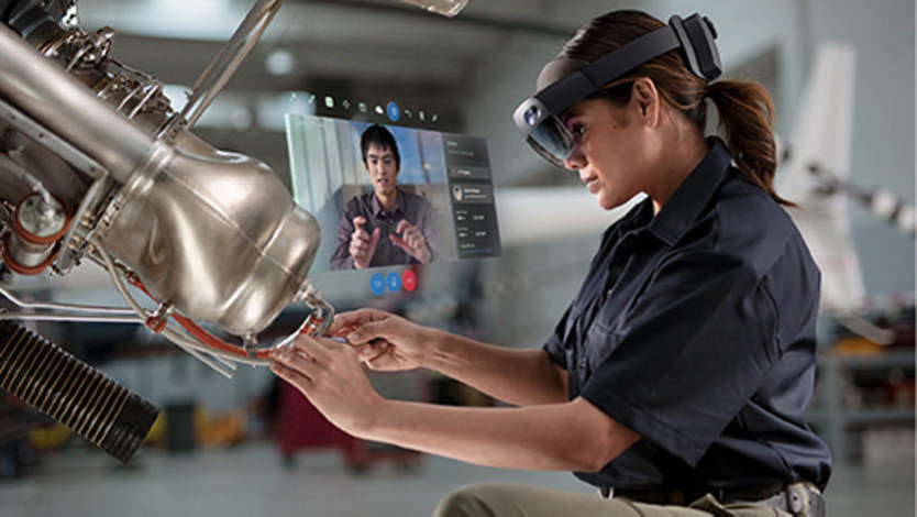 Uma mulher vestindo o HoloLens 2 trabalhando em uma peça de máquina.