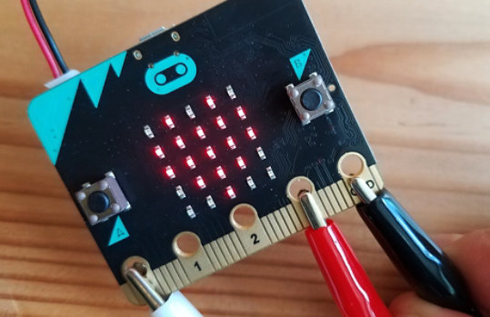 De micro:bit-chip met drie klemmen erop aangesloten.