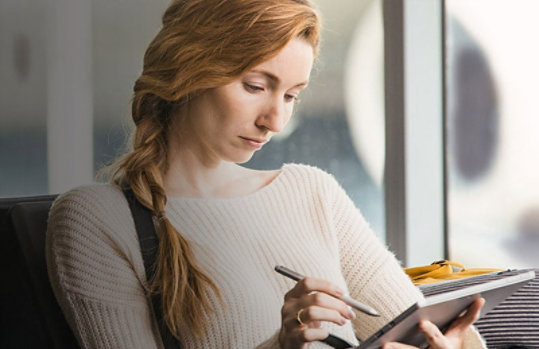 Eine Frau malt mit einem Stift auf Ihr Tablet