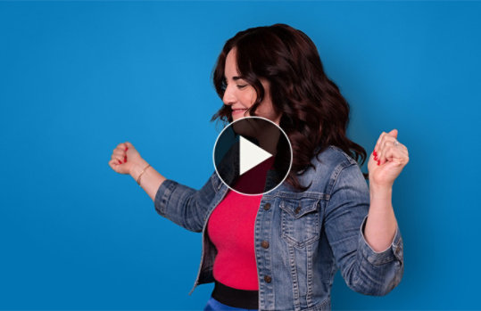 Brown haired woman in denim jacket and red shirt dancing