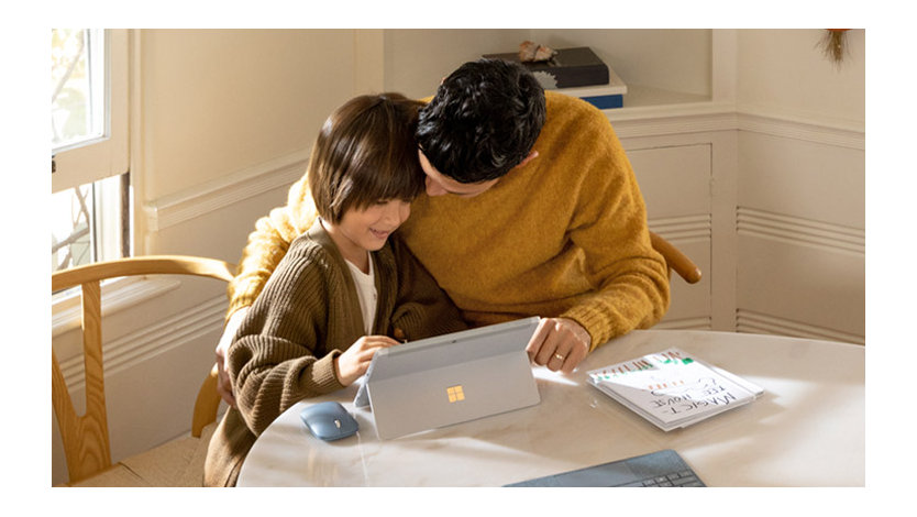 A father and daughter sitting at a round table working together on a Windows 10 PC