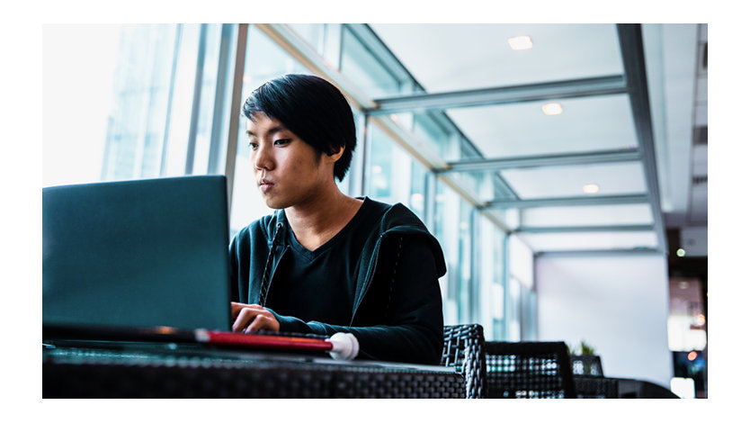 Debra Droz, a woman who is hard of hearing, wears headphones and types on a laptop